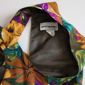 May include: A brown, green, yellow and purple floral halter top with a brown lining. The label reads "perceptions by Gary Cohen".