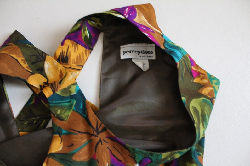 May include: A brown, green, yellow and purple floral halter top with a brown lining. The label reads "perceptions by Gary Cohen".