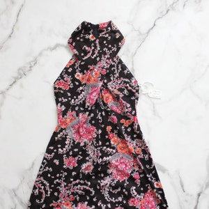 May include: A black halter dress with a floral print in shades of pink, orange, and grey. The dress has a fitted bodice and a flowing skirt.