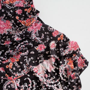 May include: A black dress with a floral print in shades of pink, orange, and white. The dress has a ruffled hem and a fitted bodice.