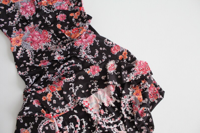 May include: A black dress with a floral print in shades of pink, orange, and white. The dress has a ruffled hem and a fitted bodice.