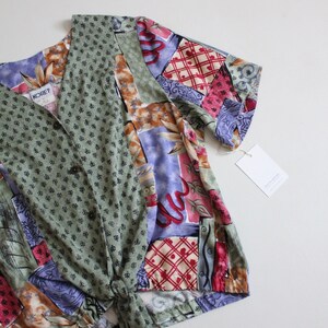 May include: A green, purple, red, and brown patterned shirt with a tie front and short sleeves. The shirt has a button closure and the label "KOret" is visible.