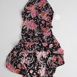 May include: A black halter dress with a floral print in shades of pink, red, and white. The dress has a ruffled hem and a fitted bodice.