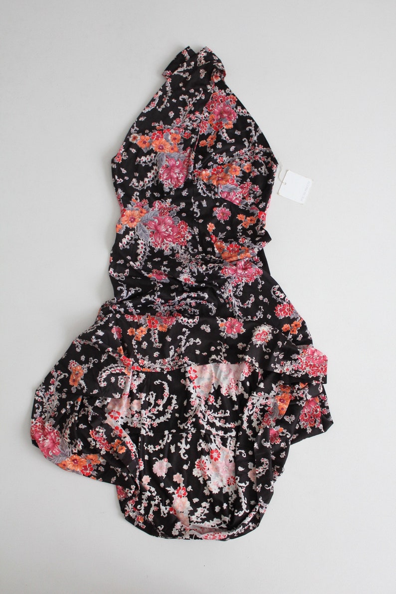 May include: A black halter dress with a floral print in shades of pink, red, and white. The dress has a ruffled hem and a fitted bodice.