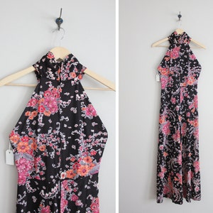 May include: A black maxi dress with a floral print in shades of pink, orange, and white. The dress has a halter neckline and is sleeveless.