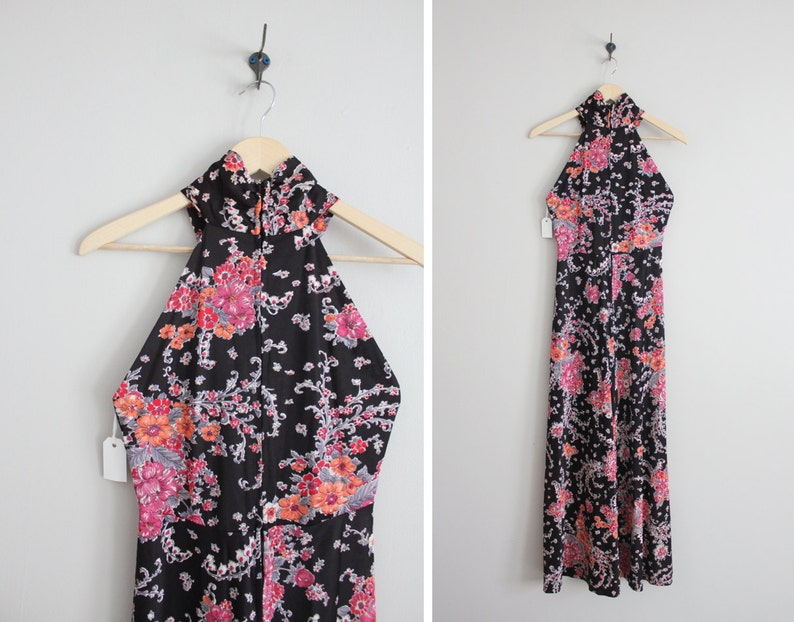 May include: A black maxi dress with a floral print in shades of pink, orange, and white. The dress has a halter neckline and is sleeveless.