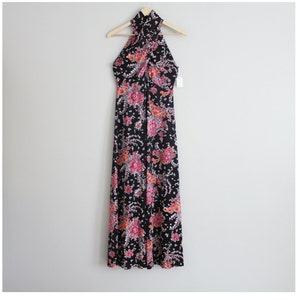 May include: A black maxi dress with a floral print in shades of pink, orange, and white. The dress has a halter neckline and a criss-cross design at the front.