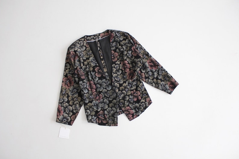 May include: A black floral print jacket with a deep V-neckline and long sleeves.