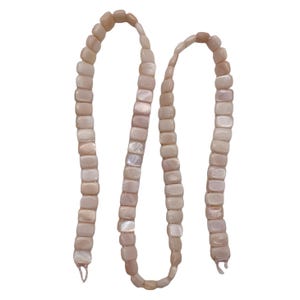 May include: A necklace composed of numerous, small, rectangular, light pink beads. The beads have a slightly iridescent quality, with hints of white and pearlescent sheen. The necklace is displayed against a white background.
