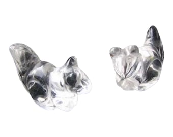 May include: Two clear, transparent squirrel figurines. The squirrels are posed in different positions, one upright and the other lying down. The figurines have detailed features, including their tails, ears, and faces. The squirrels are made of a clear material.