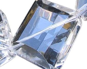 May include: Close-up of clear, faceted crystal beads. Each bead is a rectangular prism with multiple facets, creating a sparkling effect. The beads are strung together on a clear string, suggesting a necklace or bracelet.
