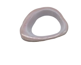 May include: A light pink, oval-shaped ring with a smooth, glossy finish. The ring has a hollow centre and a slightly irregular shape. The colour is a soft, muted pink, with a pearlescent sheen. The ring appears to be made of a solid material.