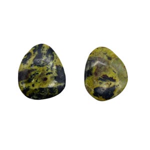 May include: Two tumbled stones with a mix of green, black, and brown colors. The stones have a smooth, polished surface and a rounded, irregular shape. The stones are likely gemstones or decorative rocks.