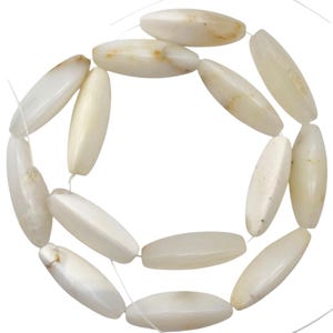 Peut inclure: Un collier de perles allongées de forme ovale, de couleur blanc cassé crème avec des veines naturelles brun clair subtiles. Chaque perle présente une surface lisse et polie, enfilée sur un fil transparent fin en disposition circulaire.