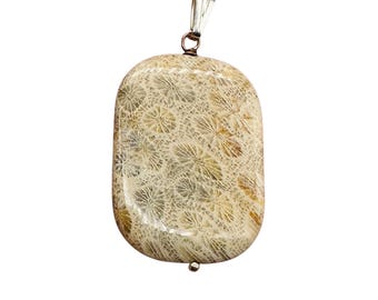 May include: A rectangular pendant with a natural, fossilized coral design. The pendant has a silver-colored bail and a small silver bead at the bottom. The coral pattern features intricate, flower-like shapes in shades of beige and tan.
