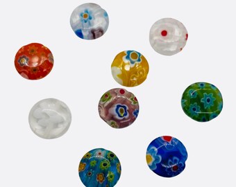 May include: A collection of nine round glass beads with floral patterns in various colors. The beads feature designs in shades of red, orange, yellow, blue, green, and white. Each bead has a unique floral pattern, with some having multiple flower designs.