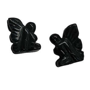 May include: Two black carved stone butterfly figurines. The butterflies are detailed with carved wings and body. The figurines are displayed on a white background. The butterflies are symmetrical and appear to be identical.