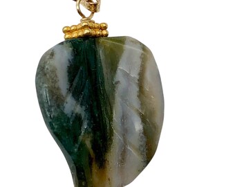 May include: A leaf-shaped pendant with a gold bail and accents. The pendant features a natural stone with green, white, and brown veining. The gold bail is attached to the top of the pendant, allowing it to be worn as a necklace.