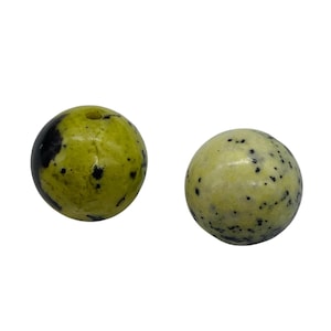 May include: Two round, polished gemstone beads. One is a light green with black spots, and the other is a darker green with black patches. The beads are smooth and have a natural, organic appearance.