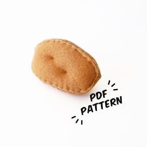 May include: A brown felt potato shaped plush toy. The toy is sewn with a simple stitch. The text "PDF PATTERN" is written in black on a white background.