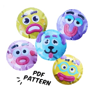 Puede incluir: Cinco caras circulares y coloridas de estilo caricatura con rasgos expresivos, incluyendo ojos móviles, labios rosas y varias formas como estrellas y corazones. Las caras son amarillas, moradas, azul claro y rosas. El texto PDF PATTERN es visible.