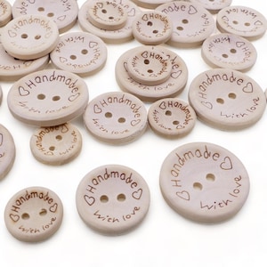May include: A collection of wooden buttons with the text "Handmade with love" engraved on them. The buttons are various sizes and are arranged in a random pattern on a white background.