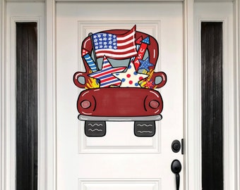 May include: Red truck door hanger with a USA flag, stars, and fireworks. The truck is decorated with red, white, and blue colors.