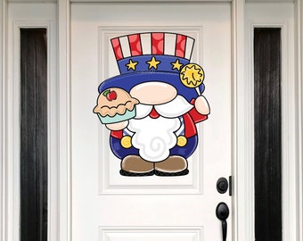 May include: A cartoon gnome wearing a red, white, and blue hat with stars and holding a pie. The gnome is wearing a blue and red shirt and has a white beard.