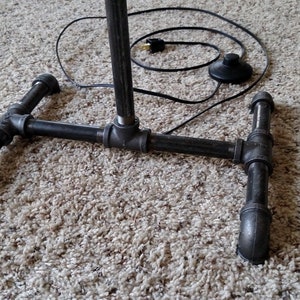 May include: Black metal pipe floor lamp with a foot pedal switch and a black electrical cord.
