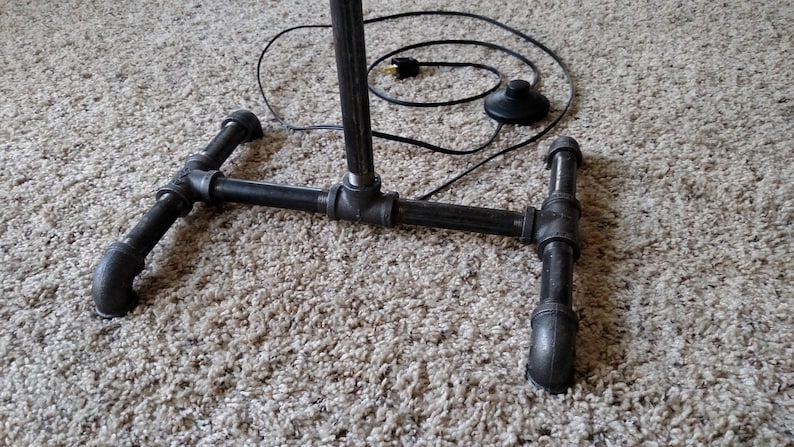 May include: Black metal pipe floor lamp with a foot pedal switch and a black electrical cord.