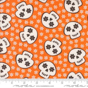 May include: Orange fabric with a repeating pattern of white sugar skulls with brown floral accents and small white and purple flowers. The fabric has a ruler along the bottom with the Moda Fabrics logo.