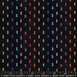 May include: A black fabric featuring a repeating pattern of small, vertical, textured dashes in vibrant shades of yellow, orange, pink, and blue. A ruler at the bottom shows a scale of 7 inches, with the text Ruby Star Society printed repeatedly.