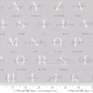 May include: A pale grey fabric featuring a repeating pattern of letters and Morse code symbols. The letters are in a handwritten style, with phonetic alphabet words below. A ruler is at the bottom, with measurements in inches.