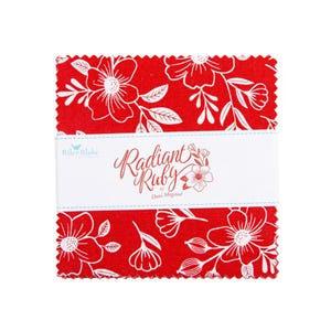 May include: A stack of red fabric squares with a white floral pattern. The fabric is wrapped with a white band that reads "Radiant Ruby" by Dani Mogstad. The Riley Blake logo is also visible.