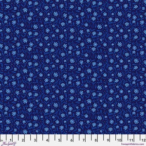 May include: A dark blue fabric featuring a repeating pattern of light blue flowers and winding stems. A white ruler is visible at the bottom, showing a scale of 12 inches. The text FreeSpirit is printed on the left and freespiritfabrics.com on the right.