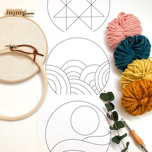 May include: A set of three embroidery patterns featuring a star, waves, and a sun. The patterns are printed on white paper and are ready to be transferred to fabric using a light box. The set also includes four balls of yarn in pink, teal, yellow, and orange.
