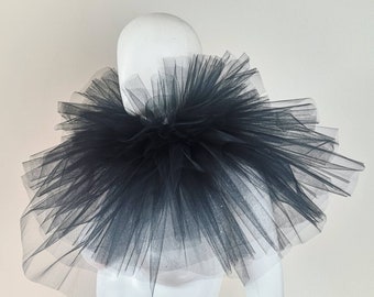May include: A black tulle collar, also known as a ruff, is displayed on a white mannequin. The collar is large and fluffy, with a dramatic, layered design. The text "Fraise au Loup" is visible at the bottom of the image.