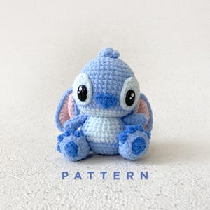 May include: A white ceramic mug with a black handle and the text "But First, Coffee" in a bold, black font. The mug is filled with a dark liquid, likely coffee, and sits on a light-colored surface.