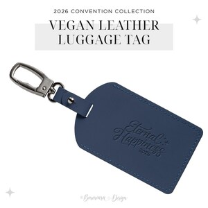 May include: A navy blue vegan leather luggage tag featuring a silver-toned metal lobster clasp. The tag is embossed with the text Eternal Happiness 2026. The top of the image includes the text 2026 CONVENTION COLLECTION VEGAN LEATHER LUGGAGE TAG.