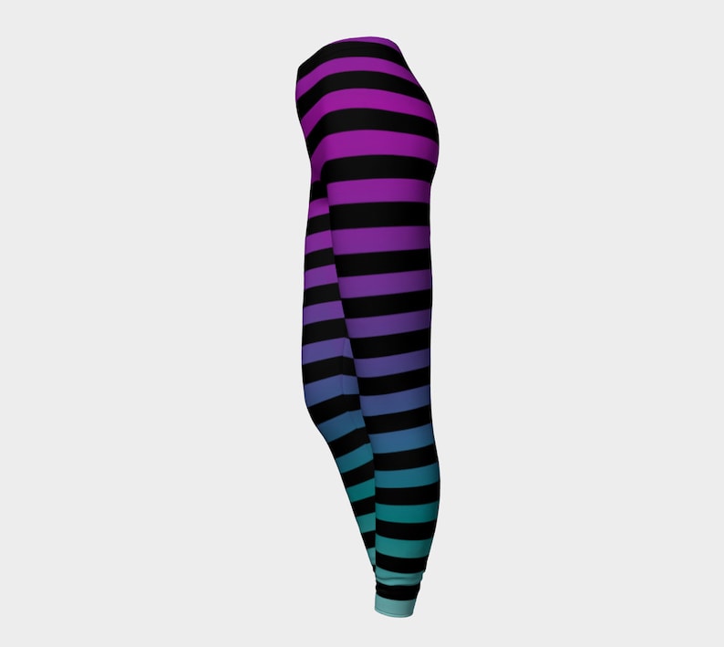 Puede incluir: Leggings largos con un patr&oacute;n de rayas horizontales que cambian de color, desde el morado en la cintura hasta el azul y el turquesa en los tobillos, intercaladas con rayas negras s&oacute;lidas en toda la prenda.