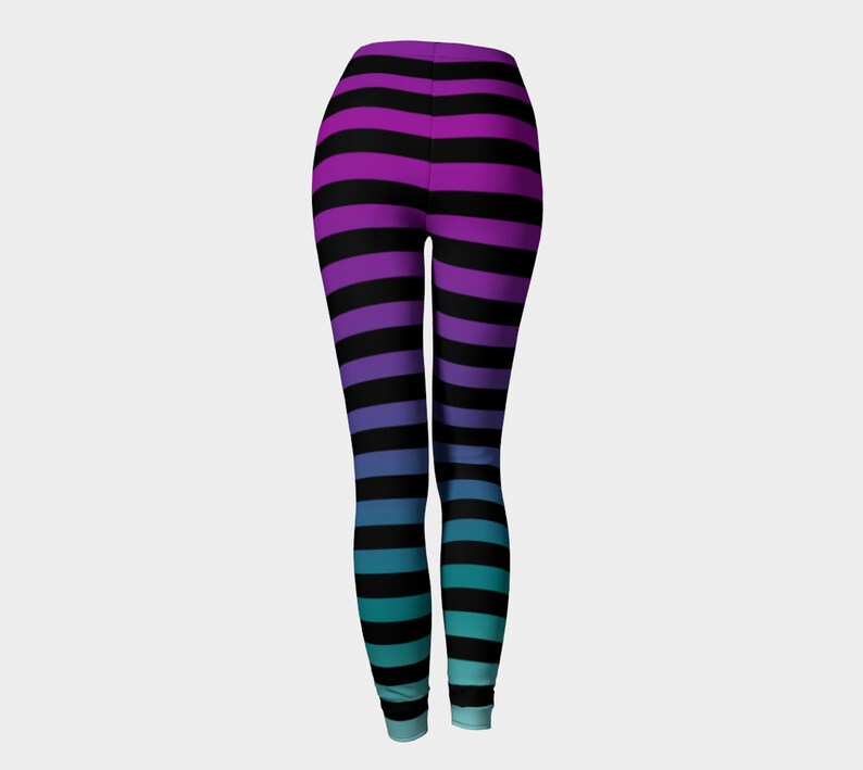 Puede incluir: Leggings de cuerpo entero con un patr&oacute;n de rayas horizontales que transicionan de color desde el morado en la cintura hasta el azul y el turquesa en los tobillos, con rayas negras constantes en todo el dise&ntilde;o.