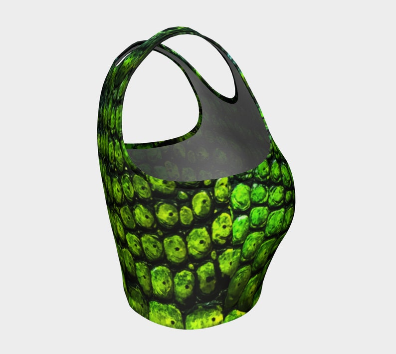 May include: Green crop top with a scaly pattern. The top has a racerback style and a cropped fit.