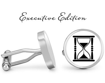May include: A pair of silver cufflinks with a white background and a black hourglass design. The cufflinks are labeled "Executive Edition".