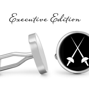 May include: A pair of silver cufflinks with a black background and a white image of two crossed fencing swords. The cufflinks are labeled "Executive Edition".