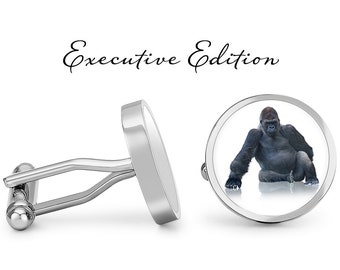 May include: Silver cufflinks with a round, white background featuring a black and gray gorilla sitting on a white surface. The text "Executive Edition" is above the cufflinks.