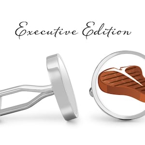 May include: A pair of silver cufflinks with a white background. One cufflink features a grilled T-bone steak illustration. The cufflinks are labeled "Executive Edition".