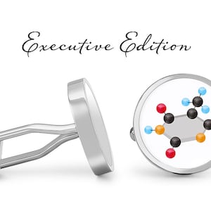 Könnte beinhalten: Ein Paar silberne Manschettenknöpfe mit weißem Hintergrund und einem farbenfrohen molekularen Strukturdesign. Die Manschettenknöpfe sind mit "Executive Edition" beschriftet.