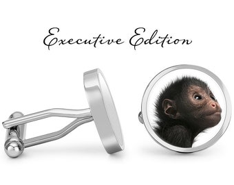 May include: Silver cufflinks with a round face featuring a black monkey with a light brown face. The cufflinks have a polished finish and the words "Executive Edition" are written above the cufflinks.