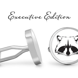 May include: Silver cufflinks with a black and white raccoon face design. The cufflinks are round and have a polished finish. The text "Executive Edition" is written above the cufflinks.