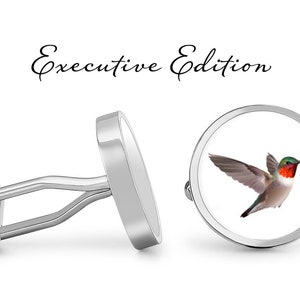 May include: Silver cufflinks with a round, white background featuring a detailed image of a hummingbird in flight. The text "Executive Edition" is written above the cufflinks.